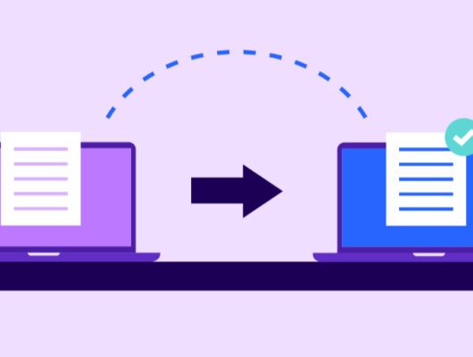 Two laptops sitting on a desk or table. There is a green checkmark on the screen of each laptop. The laptops are likely showing successful data transfer or completion of a task