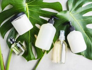 A group of cosmetic bottles in different shapes and sizes sitting on top of a monstera leaf.