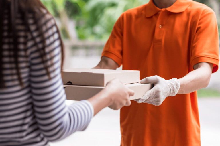A man in gloves handing home delivery of packages to a woman