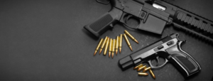 Handgun with rifle and ammunition on dark background with copy space