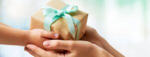 adult and child hands meeting together with small gift box with blue ribbon