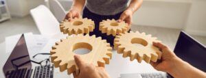 workers in office combining wooden gears in hands