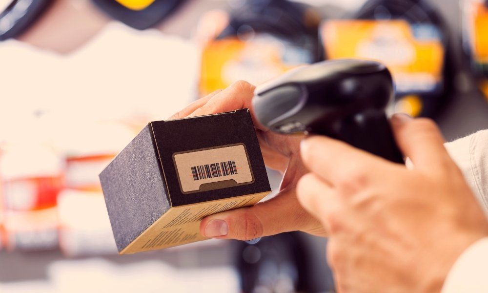 Close-up of person holding box with barcode and handheld barcode reader pointed at box