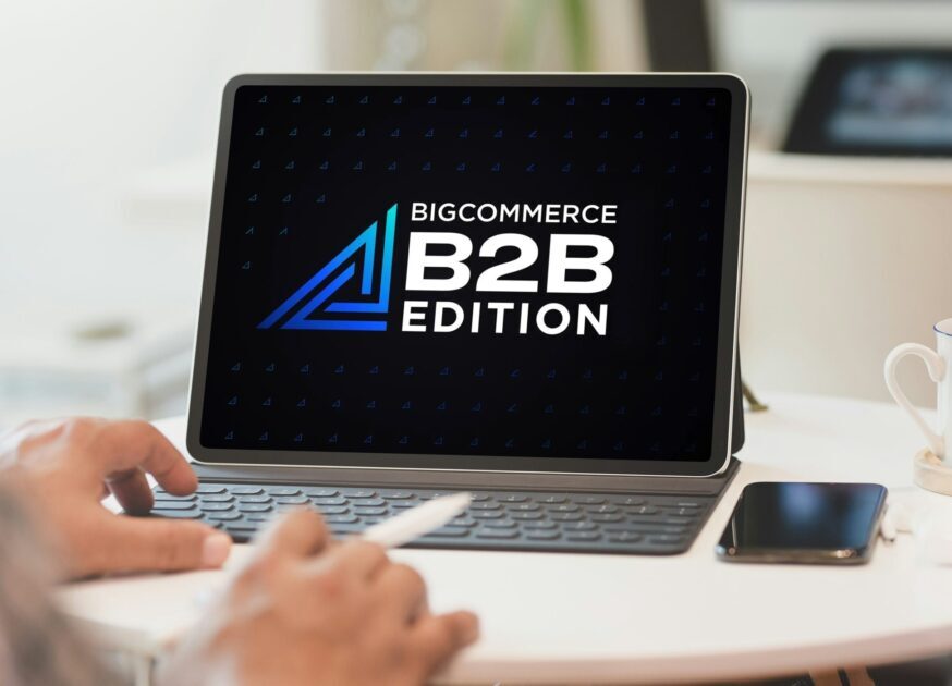 Person sitting at desk with laptop open to BigCommerce B2B Edition Logo on screen