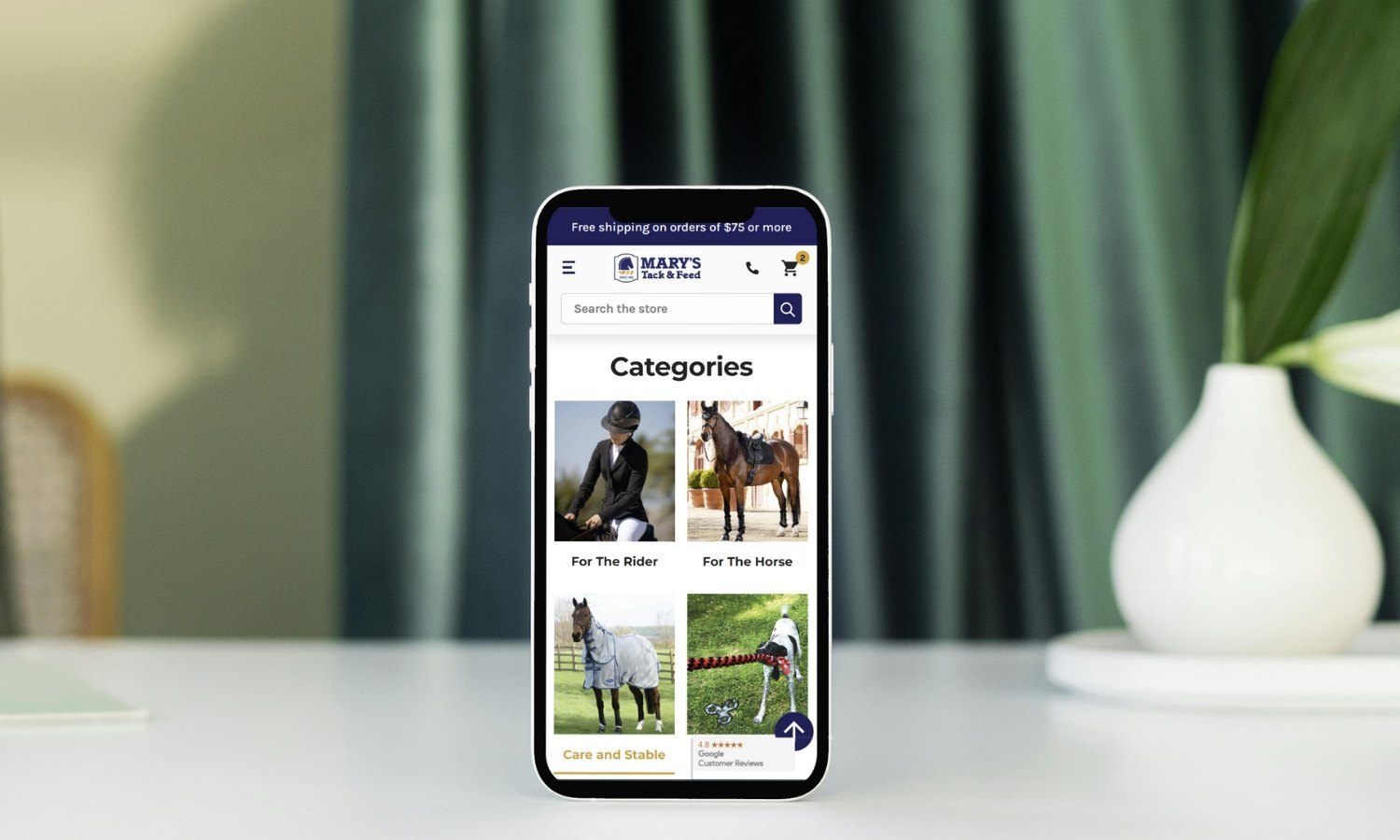 Mary's Tack homepage categories showing on mobile phone - home setting background - BigCommerce design