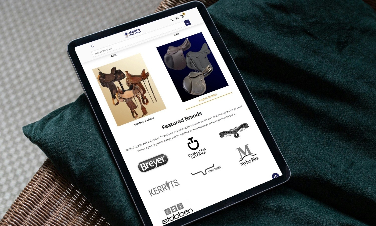 BigCommerce Design - Mary's Tack homepage on tablet sitting on pillow cushion/home setting