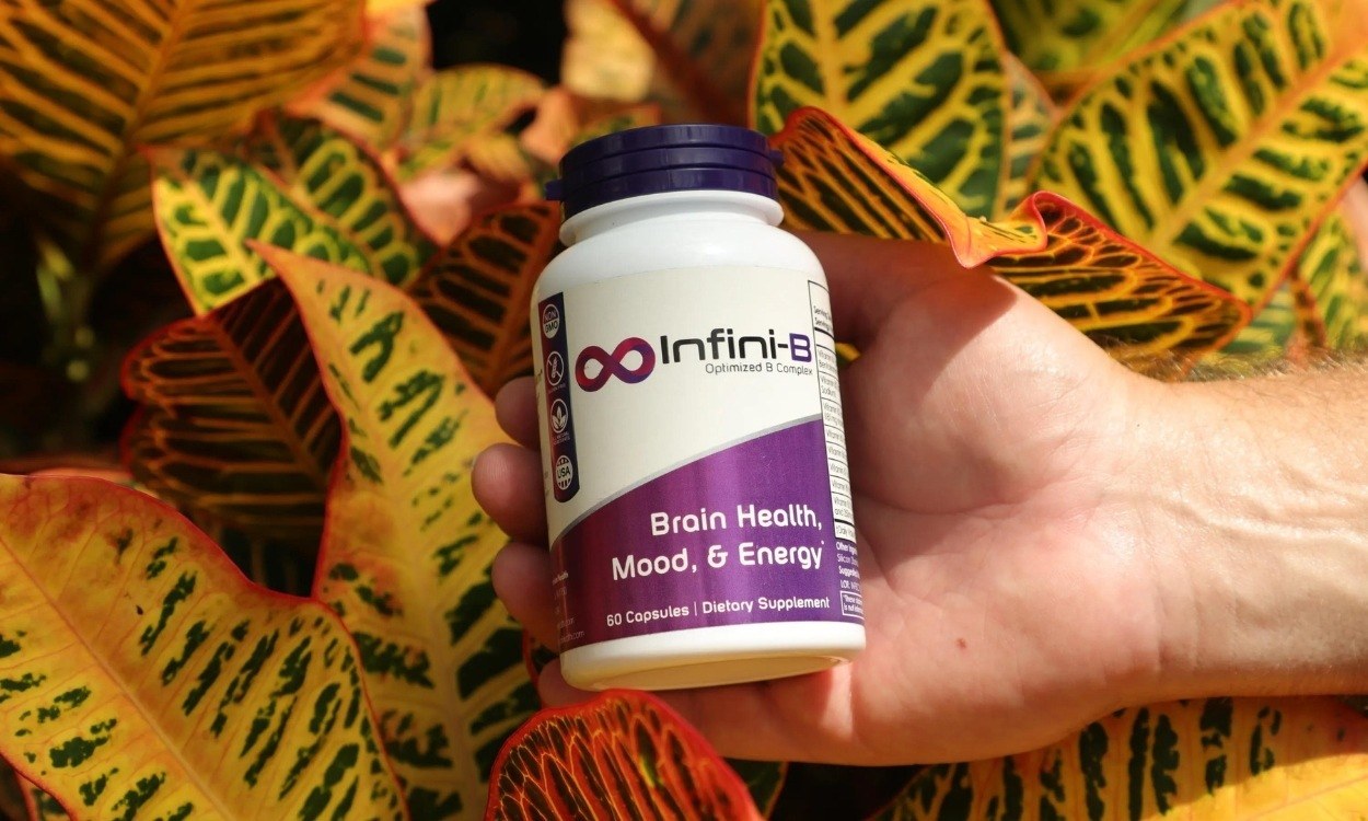 Close-up of person's hand holding bottle of Nootropics Supplement against bright foliage background - BigCommerce Design BigCommerce Development