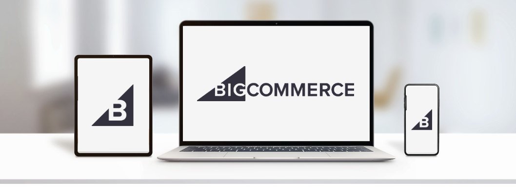 laptop, tablet, and mobile phone on white desk and blurred background showing BigCommerce logo on all screens