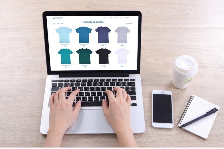 person on laptop browsing tshirts - view of hands only on laptop - BigCommerce SEO