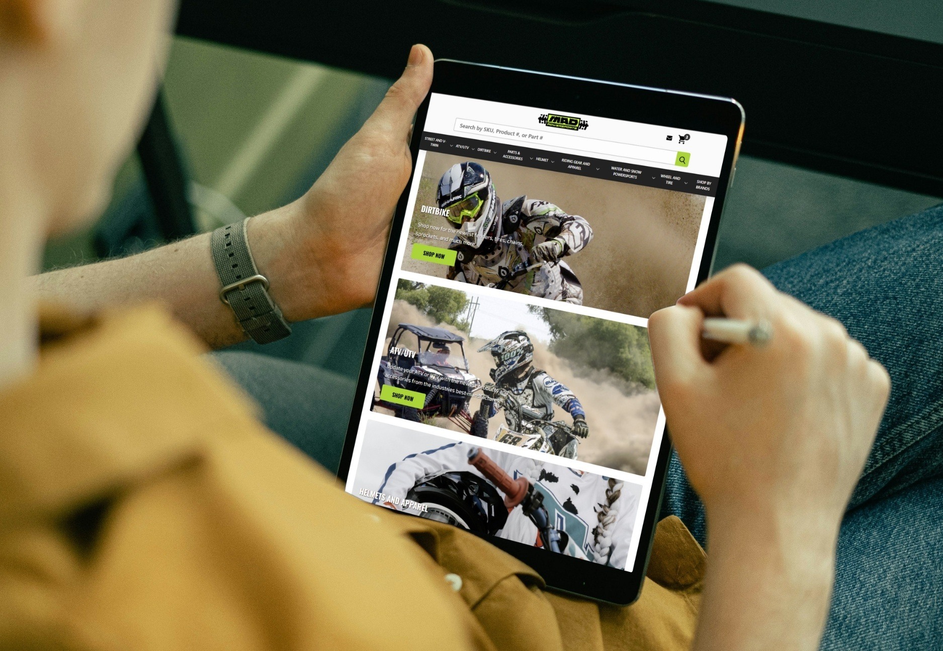 Man in yellow shirt holding tablet with homepage product categories on screen for MadPowerSports.com- BigCommerce Design BigCommerce Development