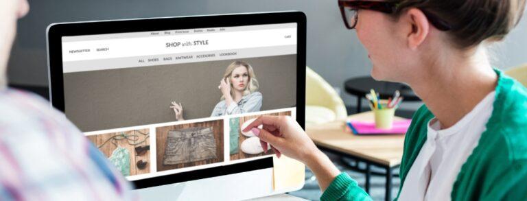 smiling woman in glasses pointing at desktop screen showing ecommerce fashion site - BigCommerce custom widget development