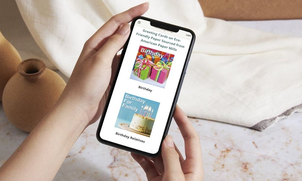 person holding smartphone against elegant cream background with screen showing Stockwellgreetings.com homepage